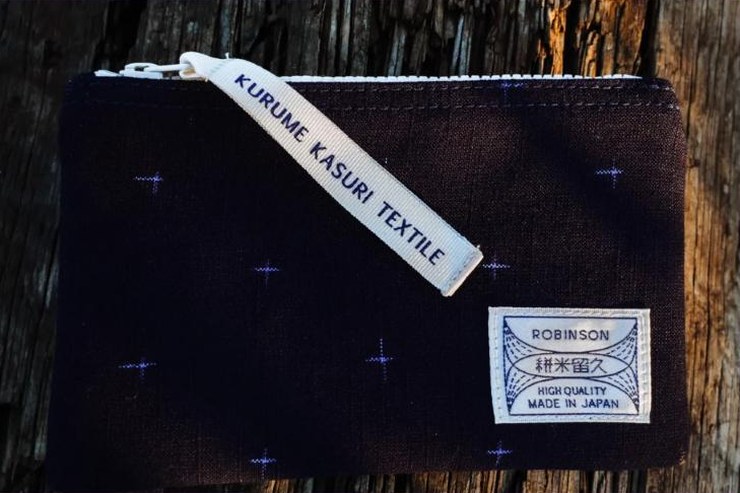 Pochette Petites croix Marine/Bleu avec son étiquette Robinson, sur du bois