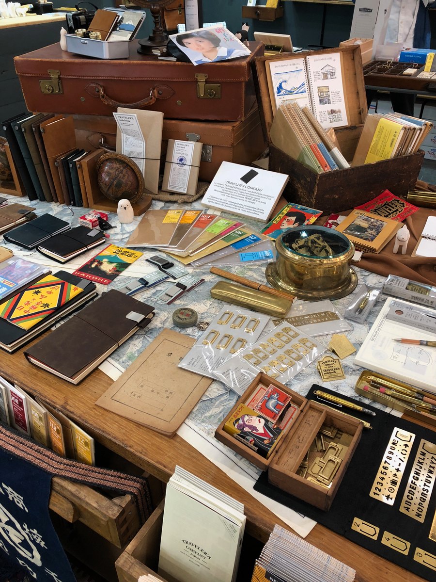 La table TRAVELER'S COMPANY sur le stand : carnets, laiton et valises anciennes